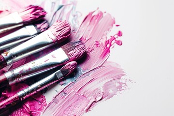 Close-up of paintbrushes resting on a palette with pink, purple, and gray paint.  The brushes are various sizes, and the paint is richly textured