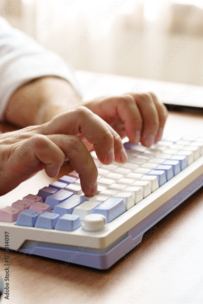 Poster person typing on a colorful keyboard at a workspace during daylight hours