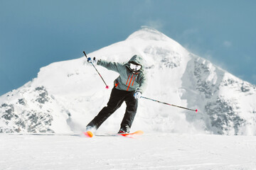 Front view skier on hilltop full speed ski downhill in sunny day in winter ski resort with mountain...