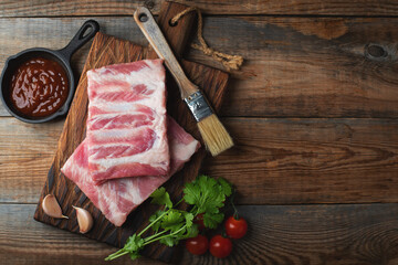 Raw pork ribs with spices, salt and rosemary on dark wooden background