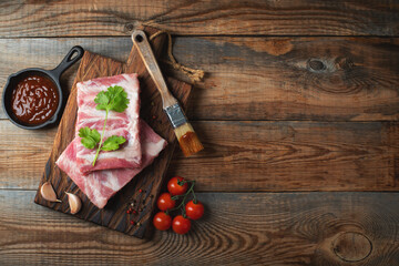 Raw pork ribs with spices, salt and rosemary on dark wooden background