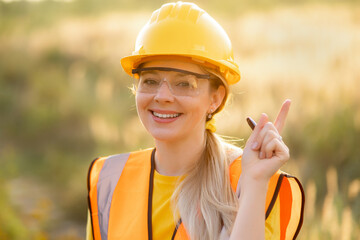 Confident female construction worker pointing upwards in high visibility vest