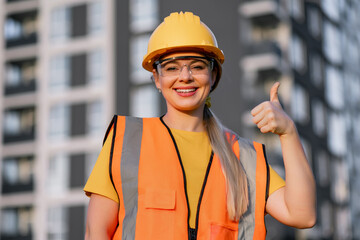 Confident construction worker giving thumbs up at urban building site