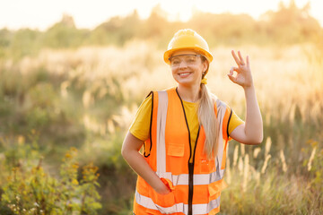 Smiling construction worker giving an okay sign in a rural outdoor setting
