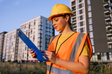 Construction worker reviewing plans on site with residential building in background