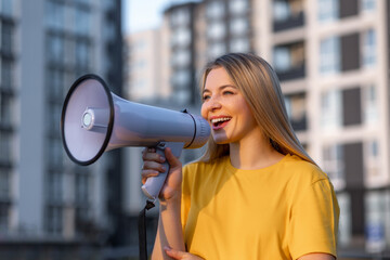 Young woman outdoors using a megaphone to make an announcement