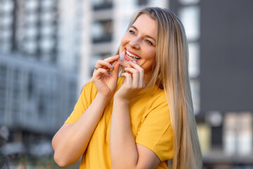Smiling woman with clear aligners outdoors in a modern urban setting