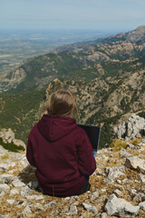 Naklejka premium Woman Working Remotely on Laptop in Scenic Mountain Landscape