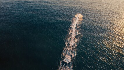 A watercraft glides smoothly across the calm ocean waters under a clear blue sky. The scene evokes...