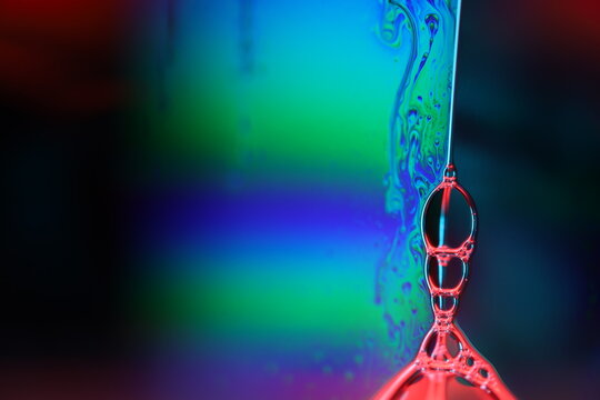 Bright multicoloured liquid surface on black background, interference pattern, soap bubble 