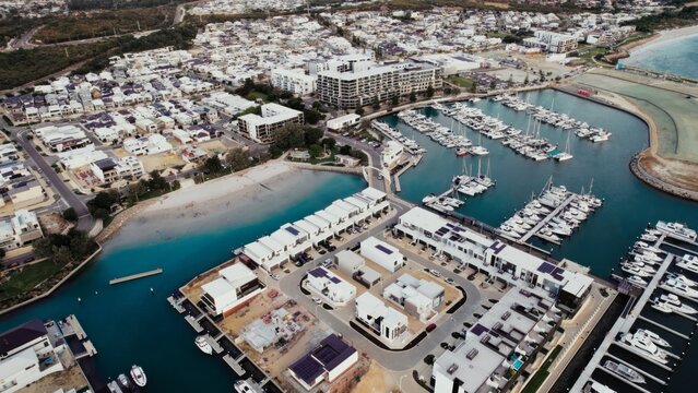 Various people of different ages and ethnicities relax by the marina in a peaceful coastal town. The serene waterfront setting enhances the affluent mood. - Powered by Adobe