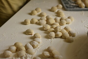 Several dumplings placed on a white table with light flour, homemade cooking scene in the kitchen.