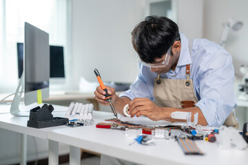 Technician repairing electronic circuit board with soldering iron in modern laboratory