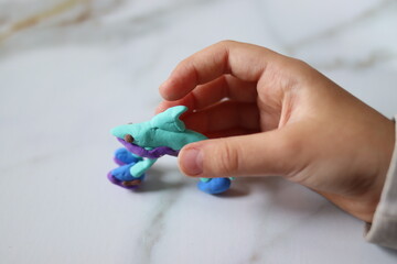 A plasticine figure made by a child in the shape of a shark in children's hands, close-up.