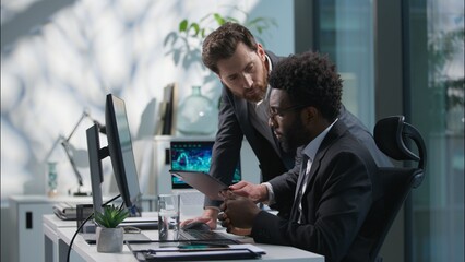 Caucasian leader boss come to African American employee multicultural diversity businessmen men males coworkers colleagues working computer tablet discussing business project teamwork guys talk office