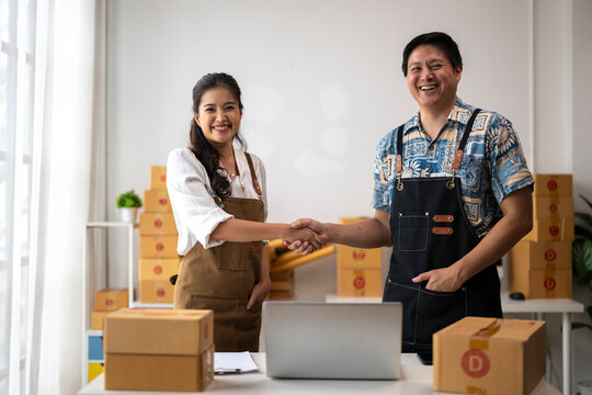 Two happy business owners shaking hands in warehouse