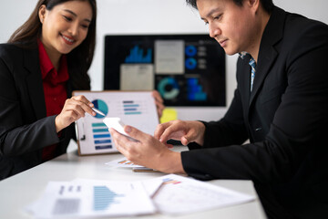 Business people analyzing charts and using calculator app on smartphone