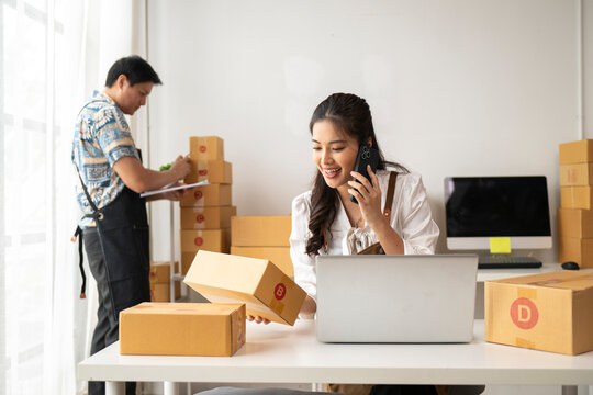 Online seller woman talking on phone and holding parcel in warehouse