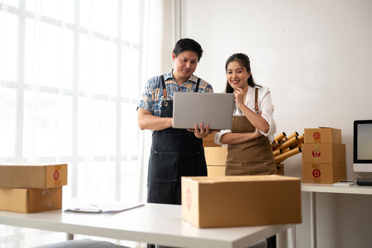 Two business owners managing online orders using laptop in warehouse - Powered by Adobe