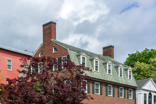Traditional red brick building with dormer windows and prominent chimneys under cloudy sky in Cambridge, Massachusetts, USA
 - Powered by Adobe
