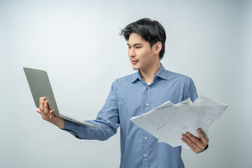 A stressed and concerned young man looks at numerous overdue bills and statements while holding a...