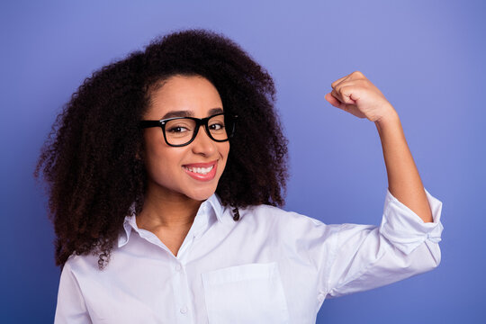 Confident young woman in white formal shirt making enthusiastic gesture while smiling, with purple background