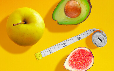 Weight loss and right nutrition concept. Measuring tape with the apple, avocado and fig. Healthy diet Pre-cooking concept. Vegetarian diet