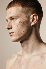 Obraz premium Minimalist studio portrait of freckled young man in profile.
