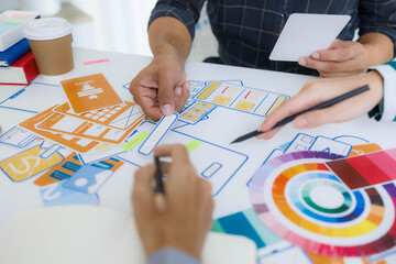 A group of people are working on a project together, with a variety of colorful materials spread out on a table. Scene is collaborative and creative, as the group works together to come up with ideas
