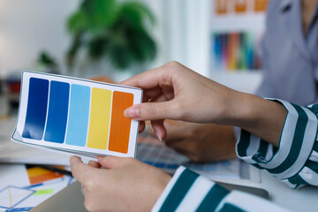 A group of people are working on a project together, with a variety of colorful materials spread out on a table. Scene is collaborative and creative, as the group works together to come up with ideas
