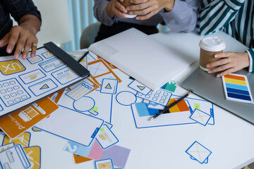 A group of people are working on a project together, with a variety of colorful materials spread out on a table. Scene is collaborative and creative, as the group works together to come up with ideas
