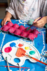 Child painting an egg box with a brush