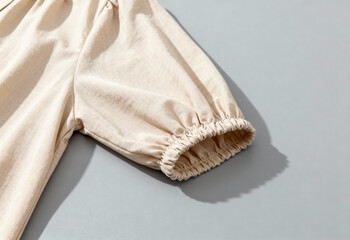 Minimalist beige blouse sleeve with gathered elastic cuff on neutral background highlighting modern casual fashion