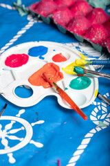 Child painting an egg box with a brush