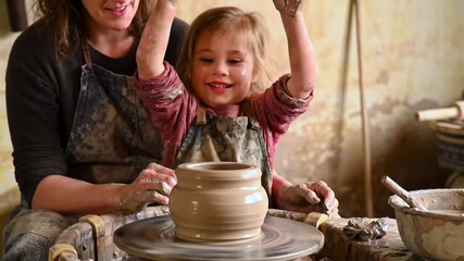 Excited young child and adult celebrate their pottery creation, enjoying a fun, hands-on learning experience together