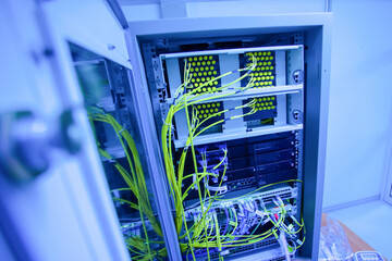 Fototapeta premium Blue Lit Network Equipment in Server Rack with Cables and Connections
