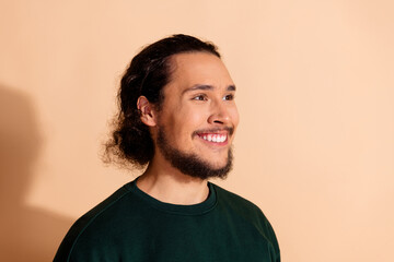 Fototapeta premium Portrait of a cheerful young man with a beard wearing a green sweatshirt on a beige background
