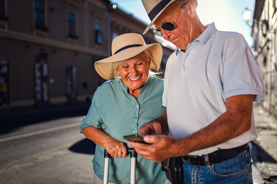 Happy senior tourist using phone for the next sightseeing destination in the city during the day.