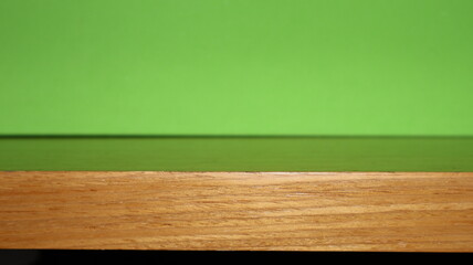 Empty wooden table top with green copy space background, for displaying the advertised product.