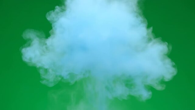 A gentle puff of soft blue color powder slowly expanding into a delicate cloud on a solid green background organic, slowly expanding, chroma key