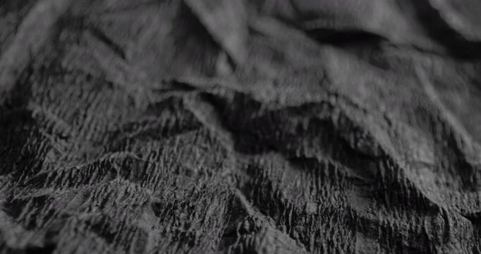 Crumpled Texture with Linear Motion. Video showing dynamic movement over a dark rough texture with crumpled details.	