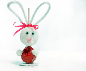 A lollipop, foam ball, and a few simple items along with a little creativity makes a fun and easy Easter bunny craft project. Displayed on bright white background.