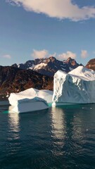 Icebergs floating in a fjord with mountains in the background