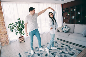 Young couple enjoys leisure time dancing together joyfully in their cozy home living area with love...