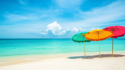 Vibrant summer beach scene with pink and blue umbrellas on sandy shore beside turquoise ocean waves. Bright blue sky with fluffy clouds creates a relaxing holiday, vacation, and travel atmosphere.