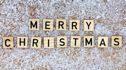Wooden blocks with the text "Merry Christmas" in top view on a snowy wooden background. Christmas card.