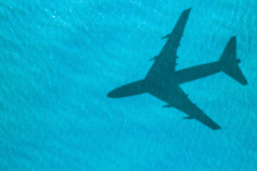 Flying airplane casting shadow on water, top view