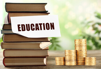 Money for education. Note, stacked books and coins on wooden table