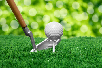 Golf ball, tee, club and green grass against blurred background
