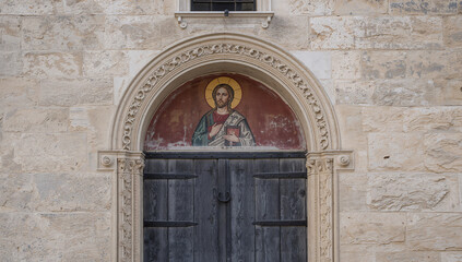 Obraz premium Religious icon above ancient wooden doors of a church.